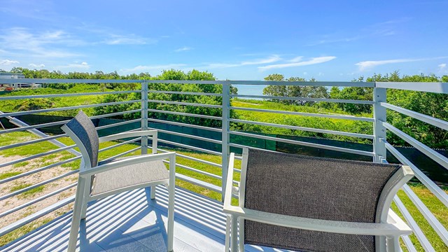 Two chairs on a balcony overlook vegetation and Florida Bay.