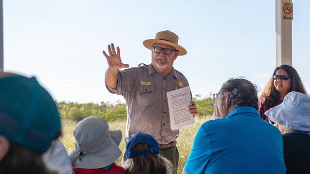 A ranger stands in front of a group of visitors.