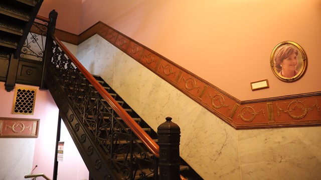 black iron staircase with a wooden banister goes to the second story of the education center