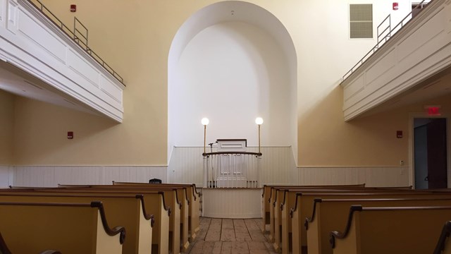 Inside of a church building with an alter and pews