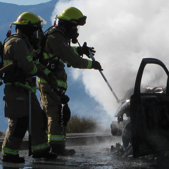 Firefighters us a hose to quell a vehicle fire.
