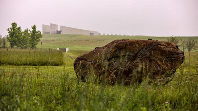 The boulder on the crash site with the Ceremonial Gate and Visitor Center shown from a distance.