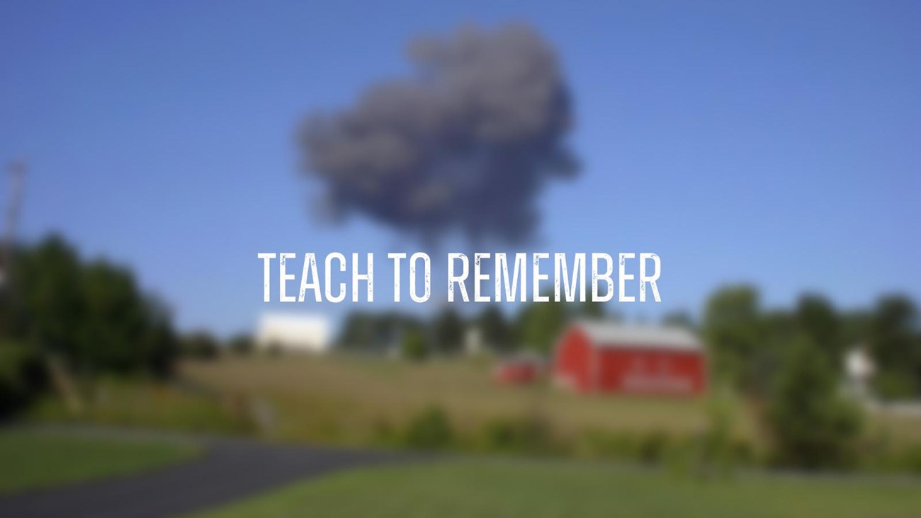 A large black smoke plume behind a red barn and a rural landscape