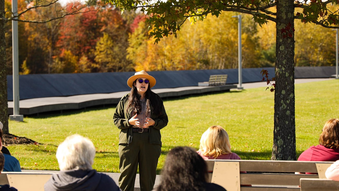 A Park Ranger speaks to visitors sitting on the benches at Memorial Plaza