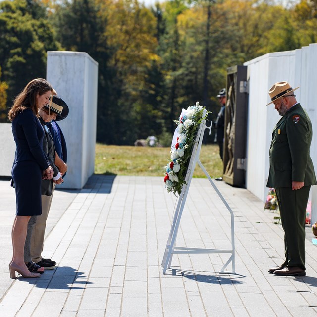 A park ranger lays a wreath in front of group of people. 