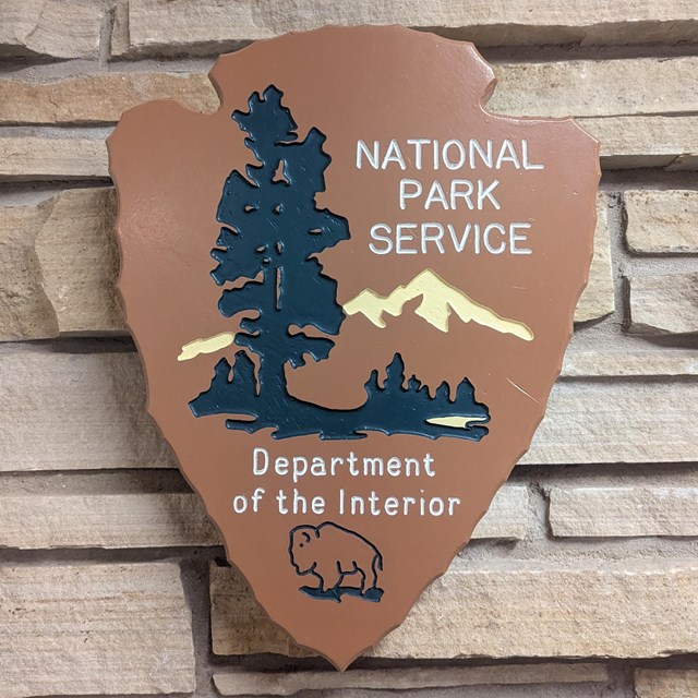 NPS arrowhead on rock wall.