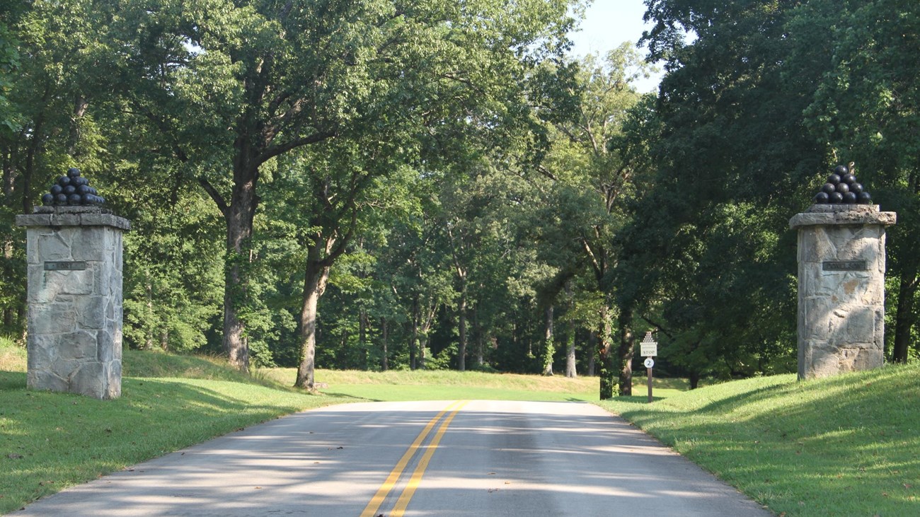 Park road goes into Fort Donelson and two pillars with stacks of cannon balls stand on each side.