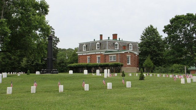 Fort Donelson National Cemetery with American Flags, monument and Caretakers house.