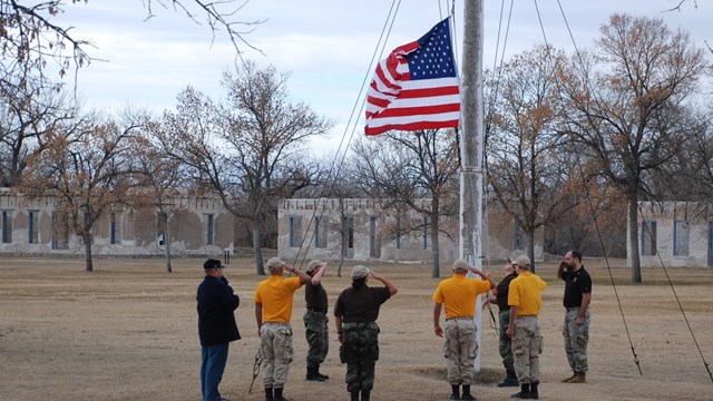 Image of several people raising the American flag and saluting. 