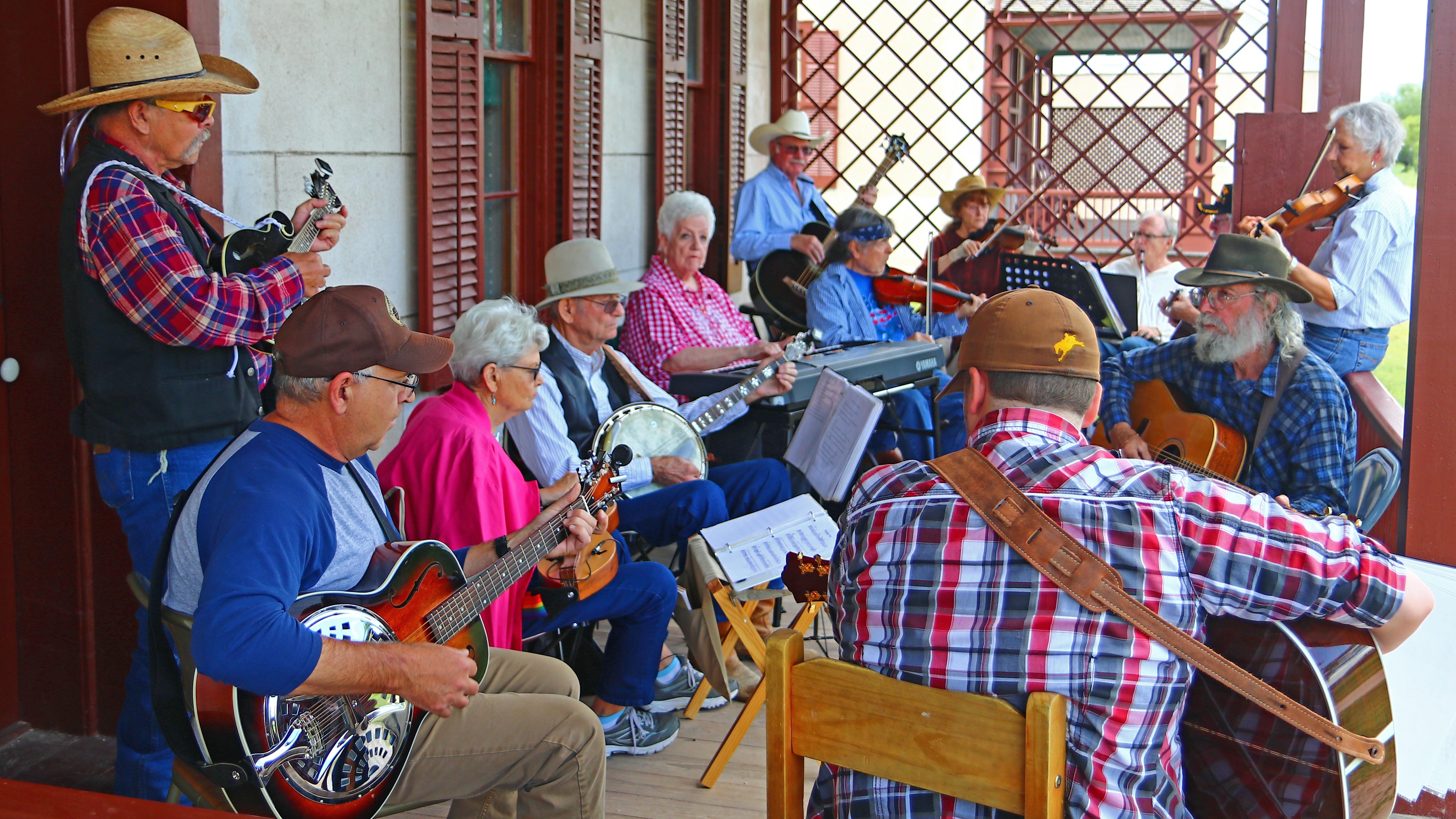 Several people gathered on a porch, playing various musical instruments and sharing a joyful moment 