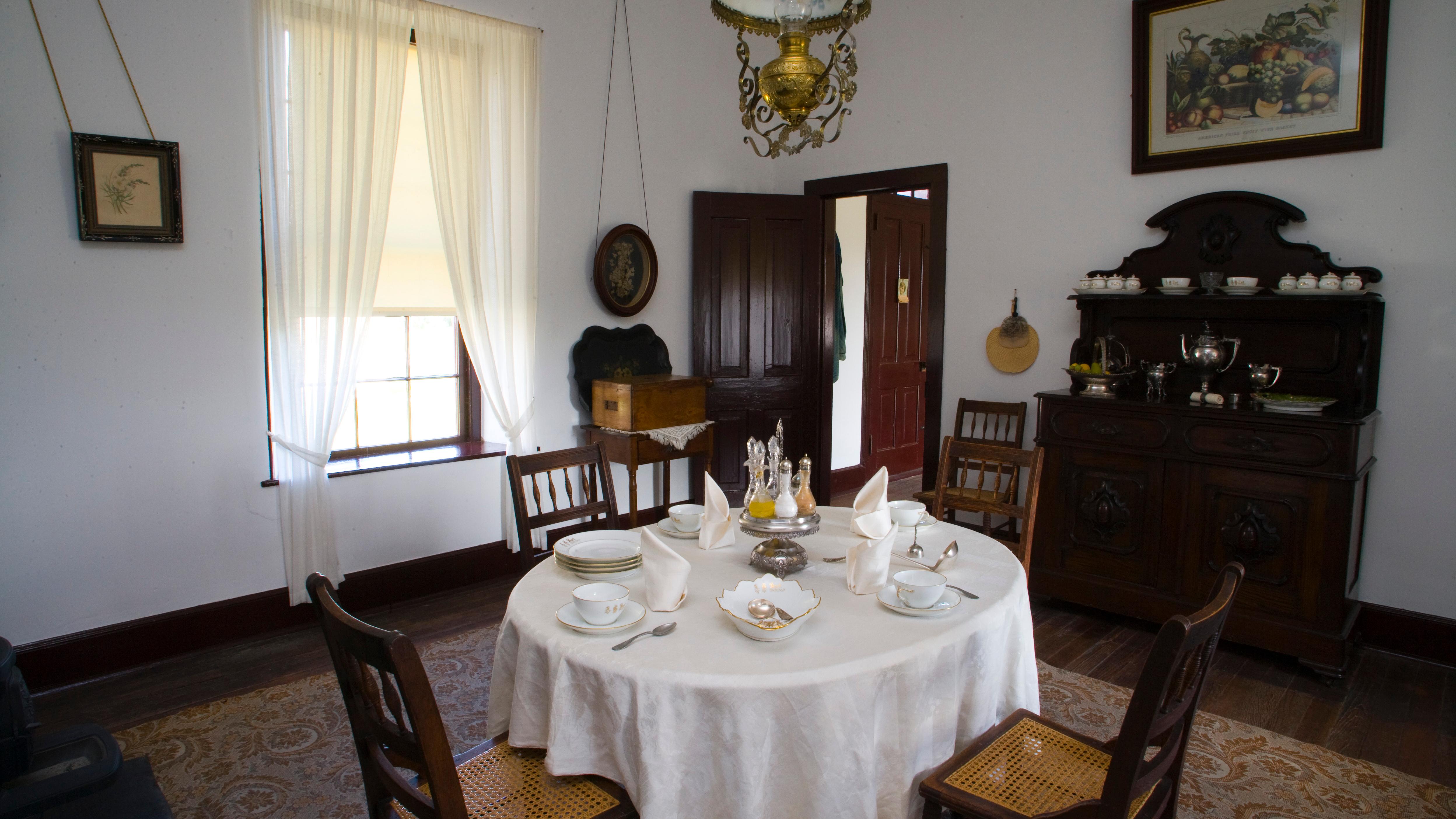 Image of interior of a historic building. The room contains three chairs and small table. 