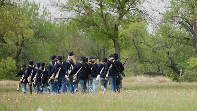 Kids dress in soldier uniform marching through the grass