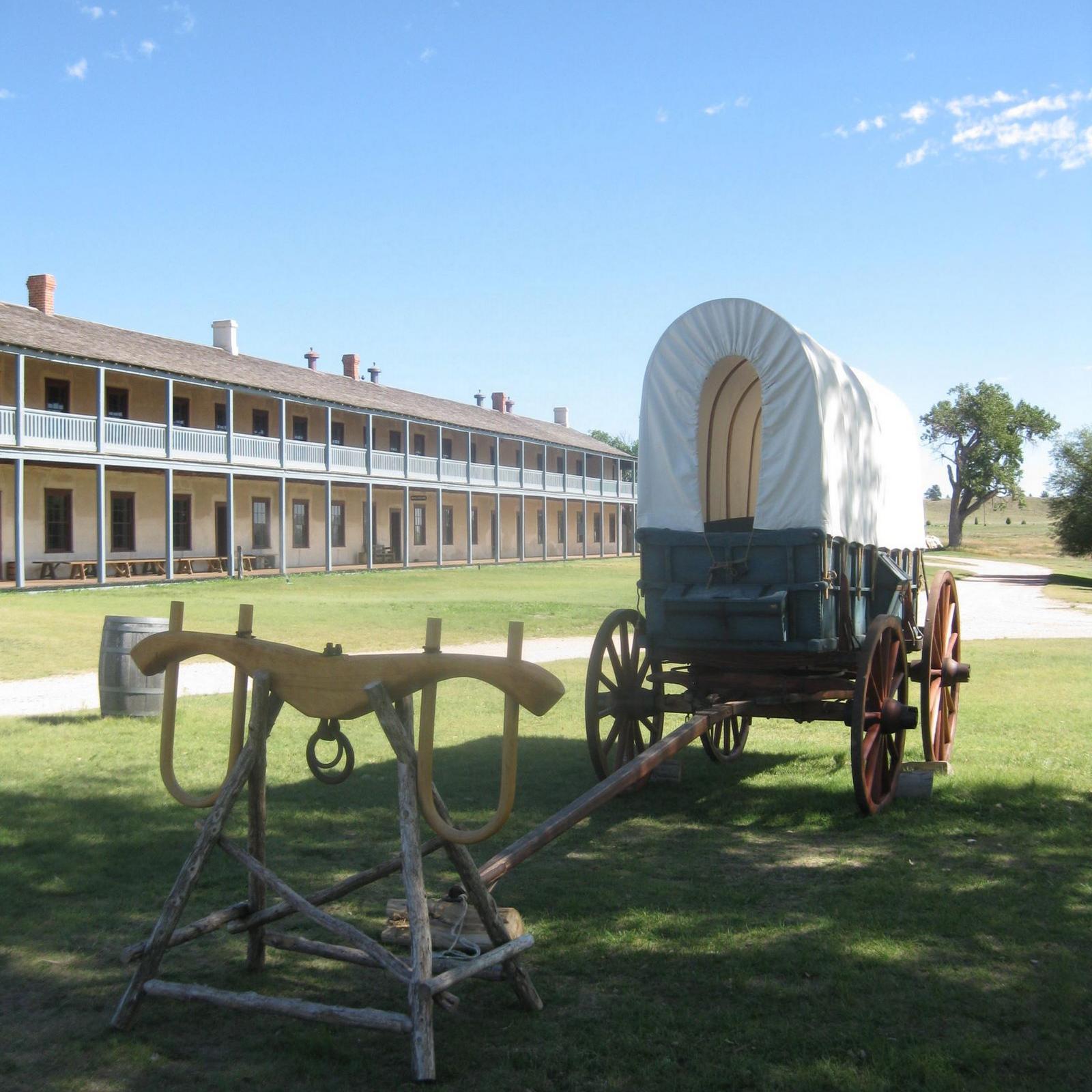 A covered wagon resting on green grass under a clear blue sky