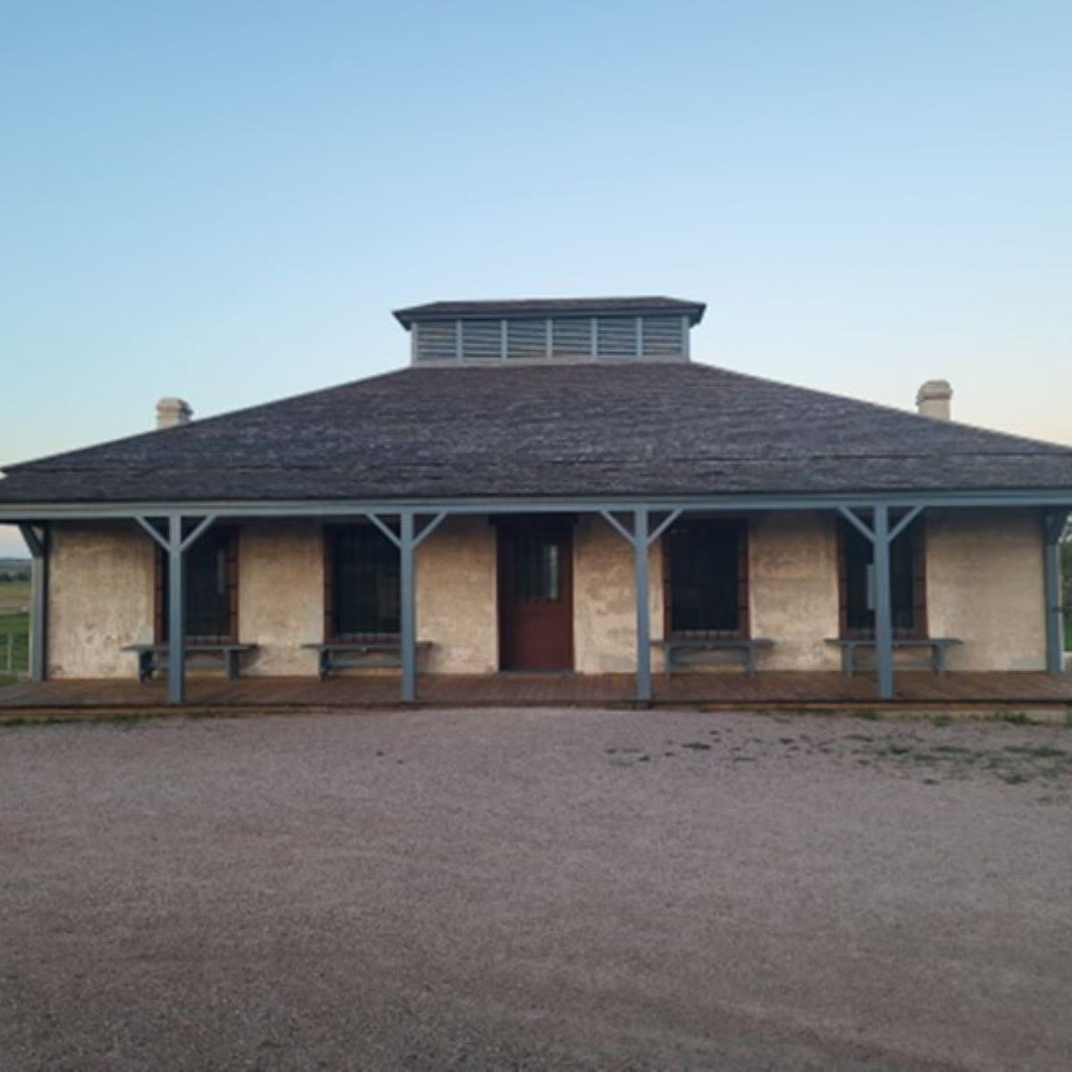 A small adobe style structure with a porch and pillars in the front. 