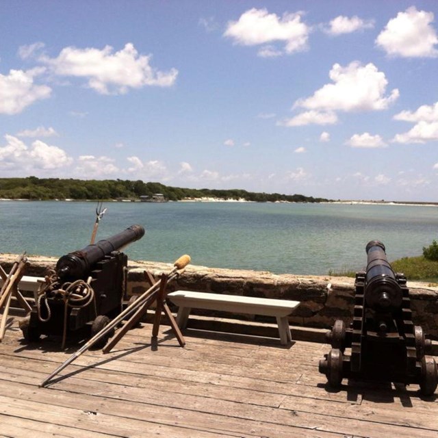 Two cannons on gun deck of the fort with river in background. 