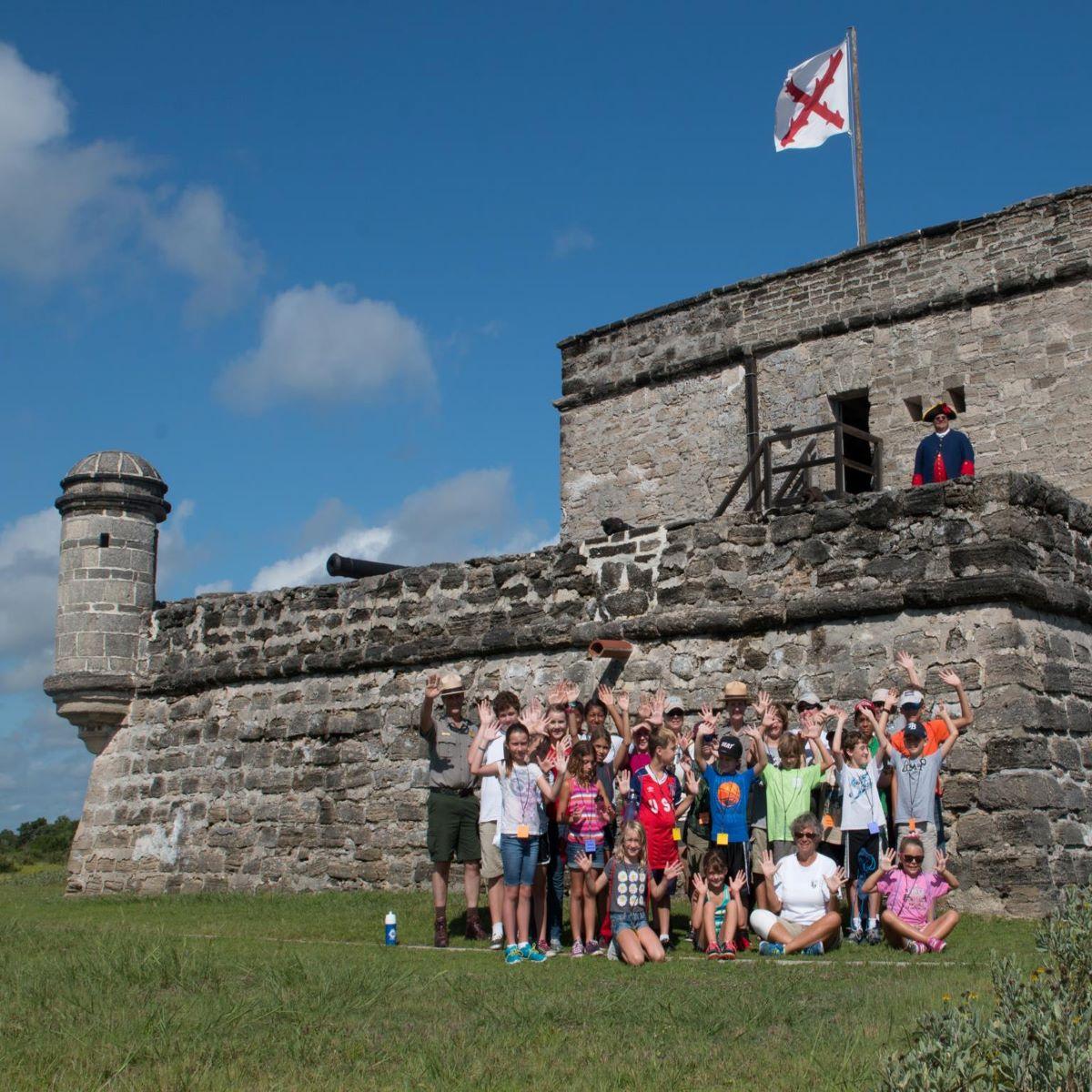 Group of students in front of fort with ranger. 