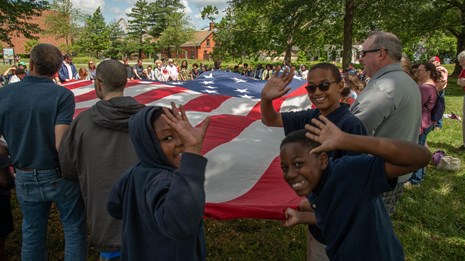Kids waving to the camera while participating in a flag talk program.