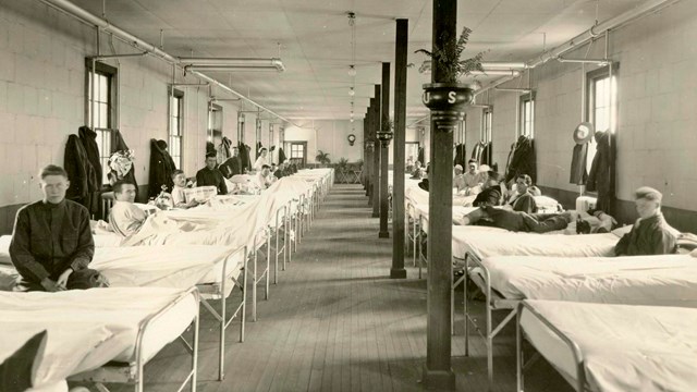 A black and white image of the inside of the hospital with patients in beds