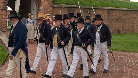 Living historians dressed as Sea Fencibles marching out of Fort McHenry.