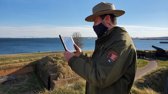 A ranger outside holding an iPad.