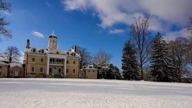 An image of the Hampton Mansion during the winter, with the front lawn covered in snow.