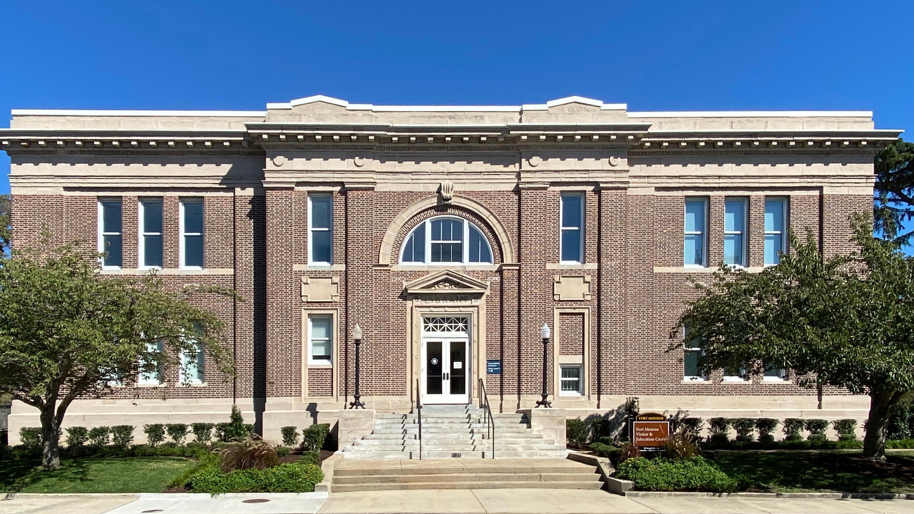 A brown brick building has a limestone foundation and trim.