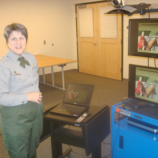 A park ranger in front of video conferencing equipment