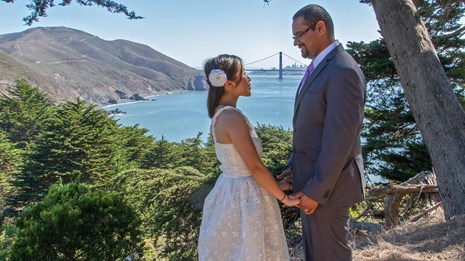 A couple in wedding attire with the Golden Gate Bridge behind