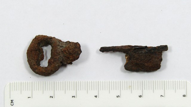 Two fragments of rusted skeleton keys on a light background. Fragments are about an inch in length.