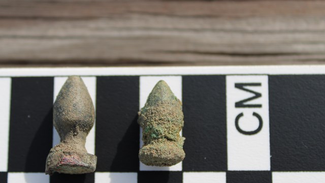 Two plumb bobs on a scale, showing they are approximately one by three centimeters.