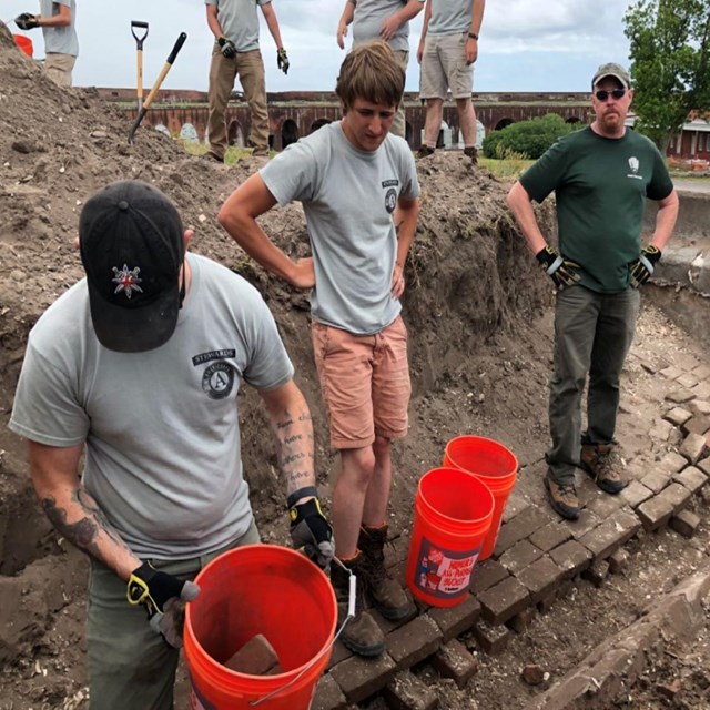 Workers standing over excavated top of Fort