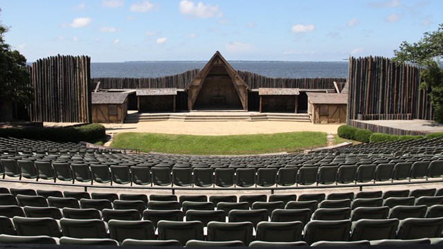 A open-air theater overlooking a body of water. The stage is made to look like buildings