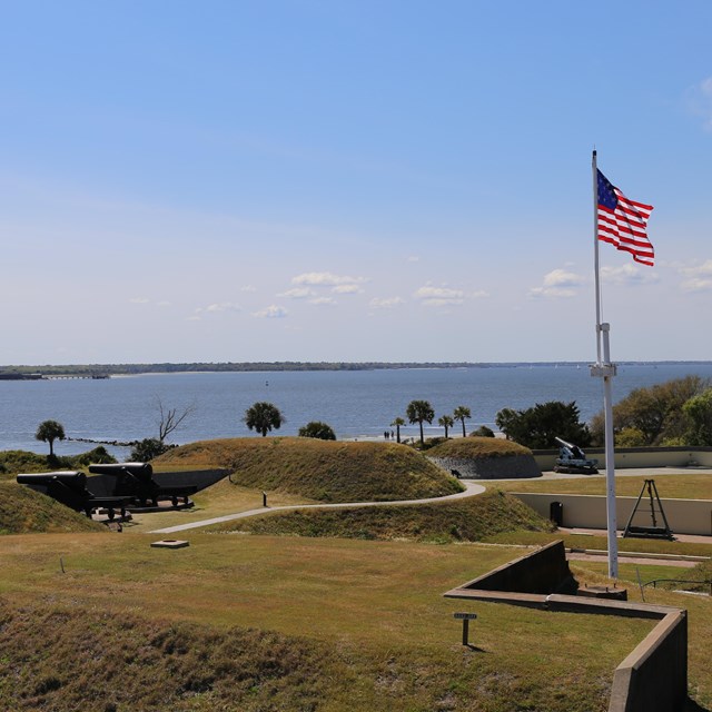 an American flag over the green tops of a fort