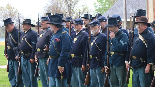 Several reenactors dressed in blue Union uniforms standing on parade ground at Fort Scott