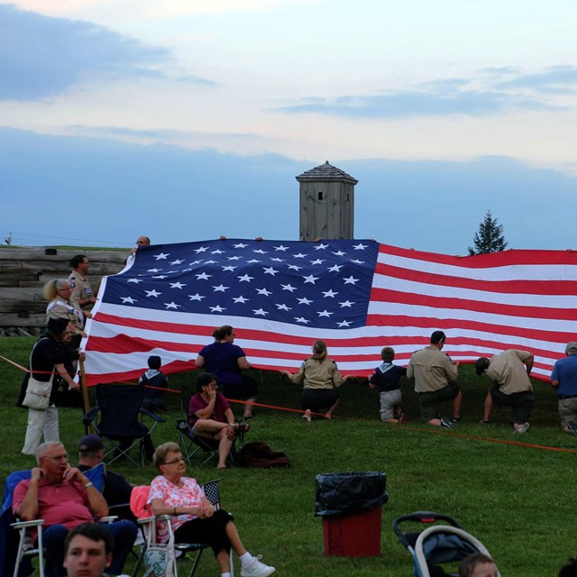 A GIGANTIC American flag is held by a group of people. 