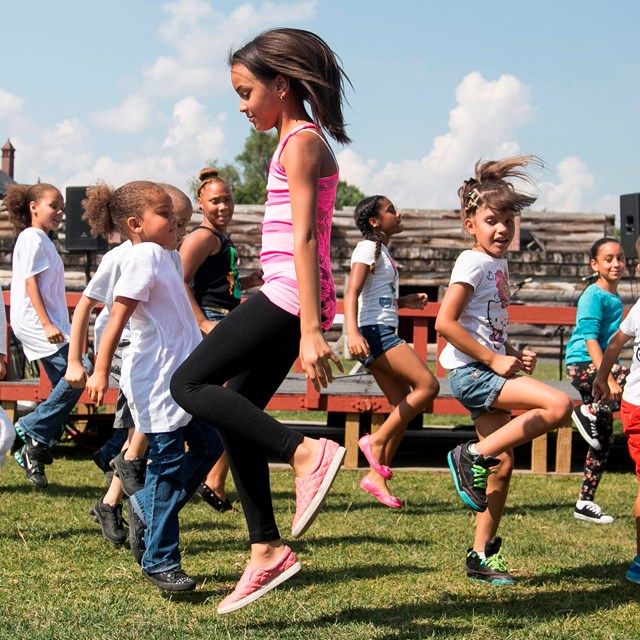Children dance, jump and skip on the parade ground of reconstructed Fort Stanwix.