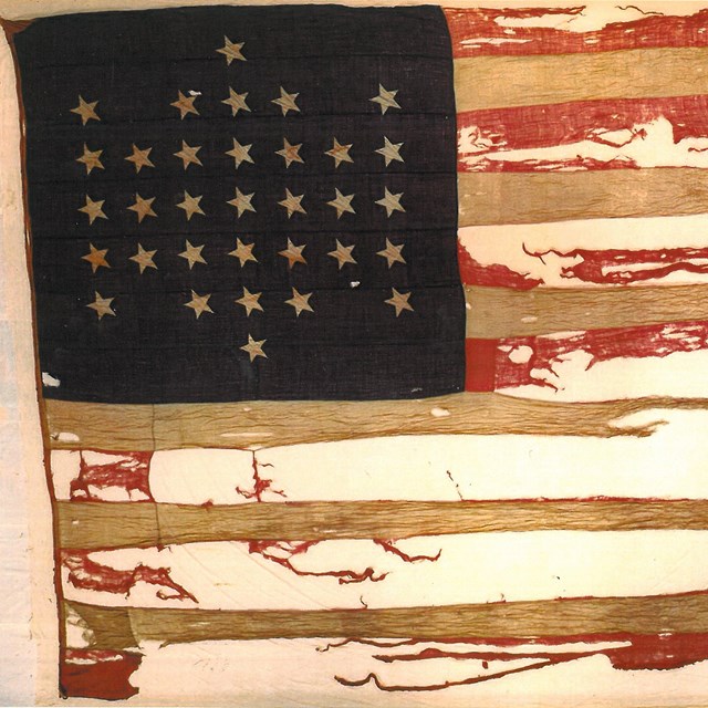 A 33-star United States flag, torn heavily side-to-side.