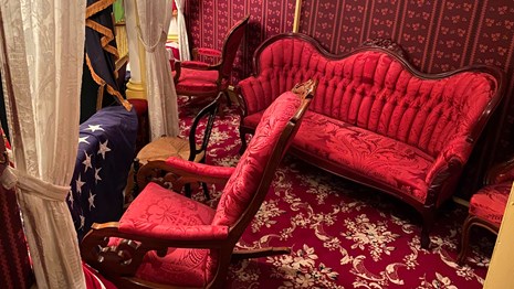 Theatre Box with red carpet, wallpaper, and red upholstered Victorian furniture.