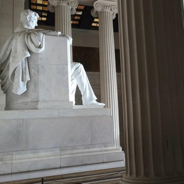 View inside Lincoln Memorial with Lincoln statue, large columns, and crowds of visitors.