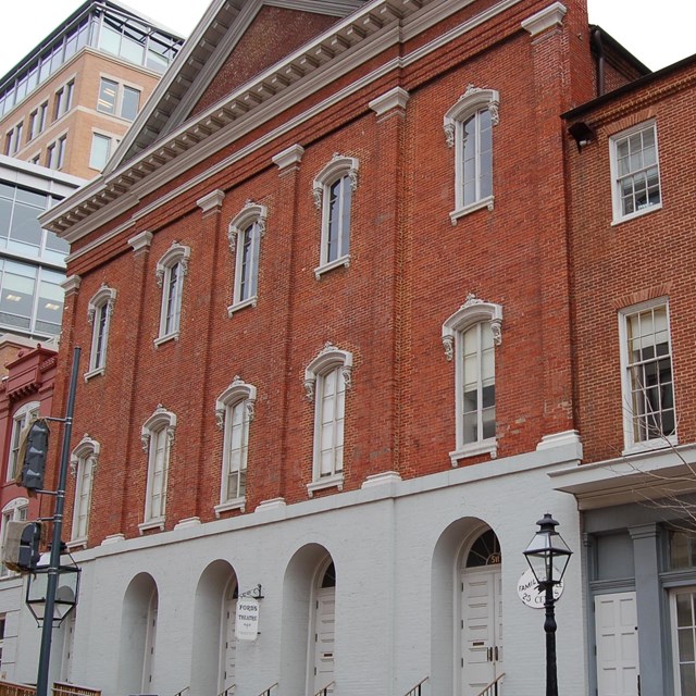 Front exterior of the red brick Ford's theatre, with 2 rows of 5 windows and 1 row of 5 doors