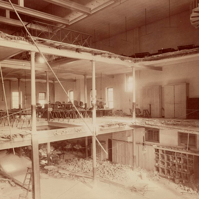 Interior of the Ford's Theatre building with a large section of floor missing. Rubble at the bottom.