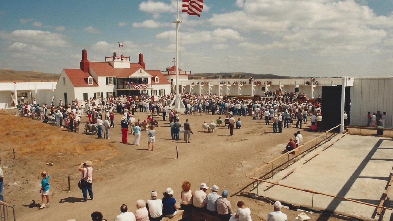 Bourgeois House and large flag flying from Flagpole, visitors wandering in courtyard.