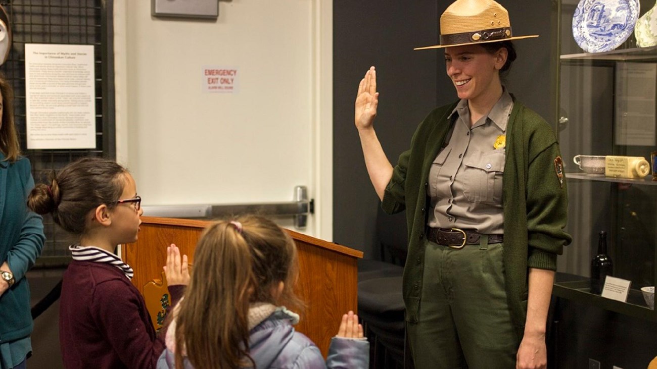 A park ranger swearing in two young junior rangers.