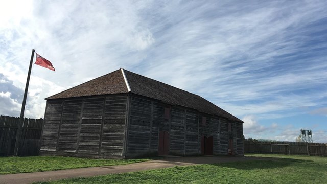 A large wooden building with a Hudson's Bay Company flag outside it.