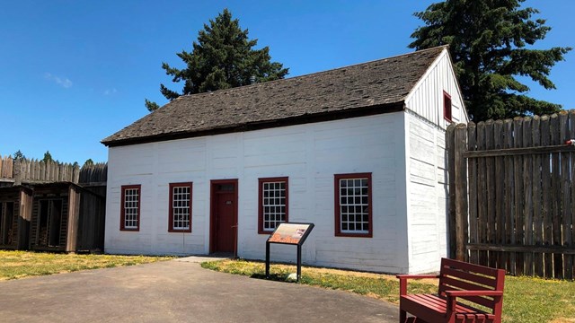 A white building with one entrance and windows.