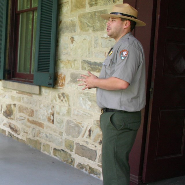 Park ranger speaking to a group on the front porch of the Gallatin House