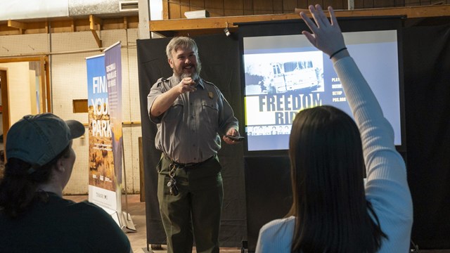 A ranger stands answers visitors' questions before a video presentation.