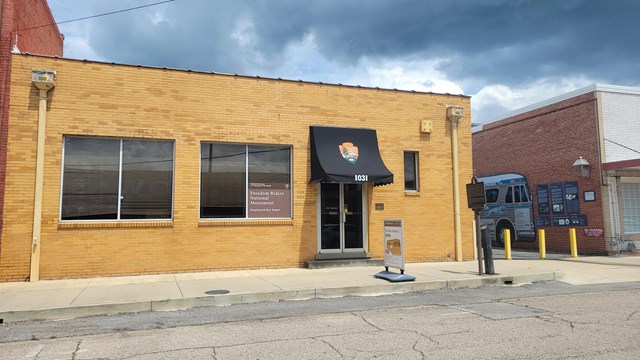 A brick building on the side of a city street with a bus mural on the building to the right.