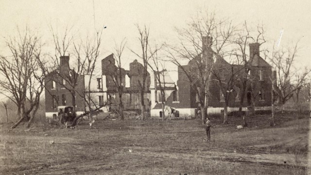 Historical photo of a large house with battle damage.
