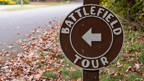 Two, stacked circular signs directing people on a Battlefield Tour.